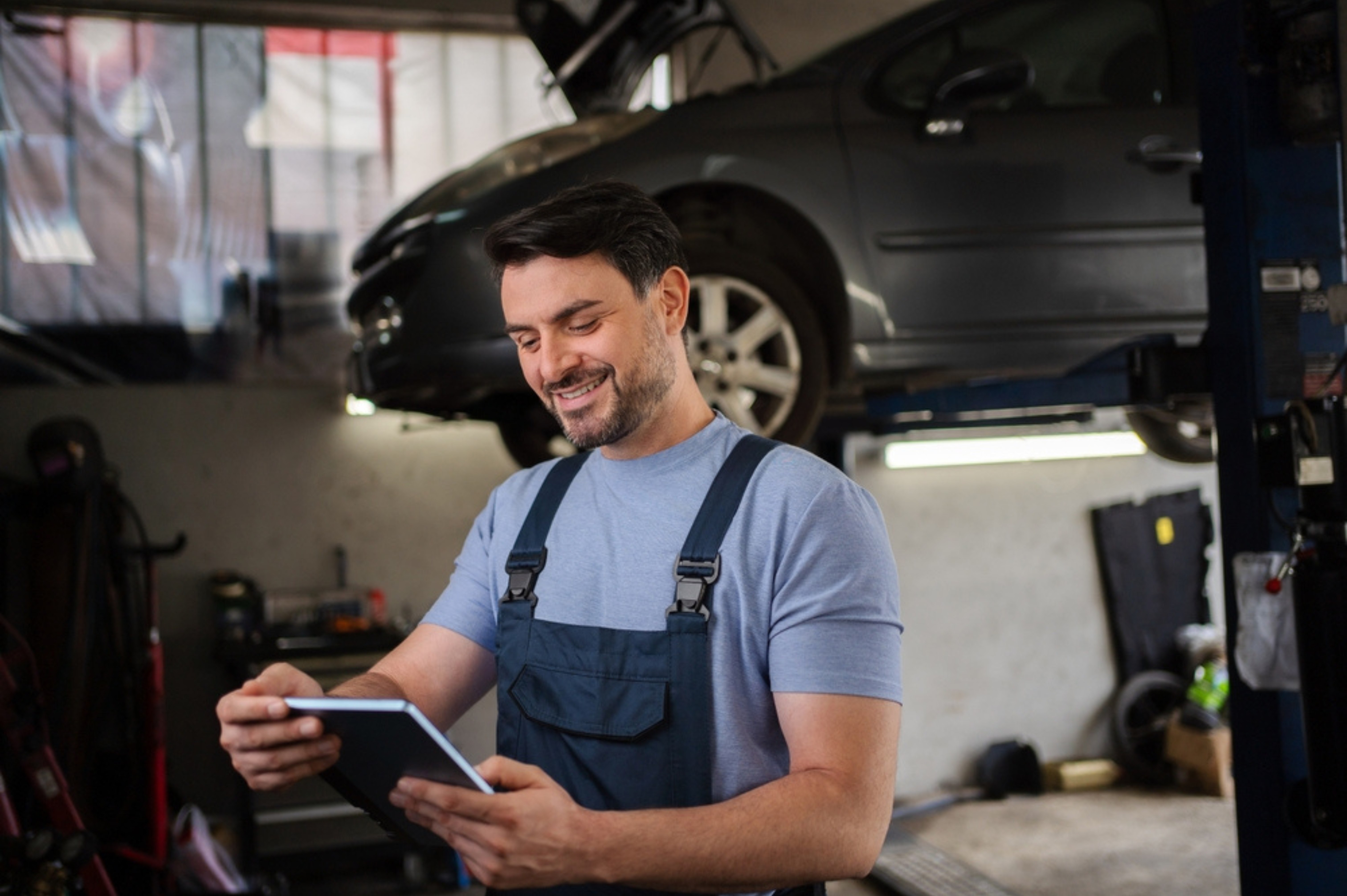 Smiling mechanic reviewing diagnostic results on a tablet in a repair shop